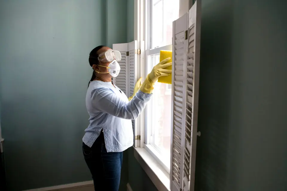 Cleaner wiping a window in a bright home